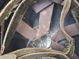 a helmet with a leather strap on it sitting on the ground