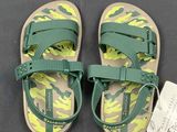green and yellow sandals with a tag on them on a black surface