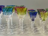 twelve multicolored wine glasses lined up in a row on a white surface