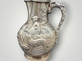 an image of a silver vase with a bird on the handle