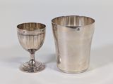 a silver cup next to a silver cup on a table