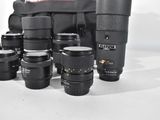 a lot of camera lenses and a bag on the table
