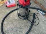 a red and black vacuum sitting on the concrete
