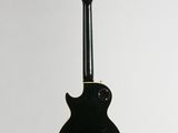 a black electric guitar hanging from a white wall
