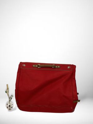 un sac rouge posé sur une surface blanche, à côté d'un petit lapin blanc