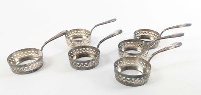six cuillères en argent et une cuillère doseuse posées sur un plan de travail blanc