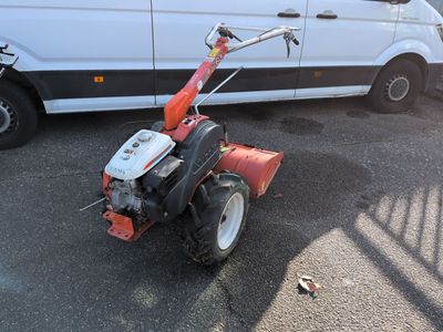 a small red and white tractor parked next to a white van