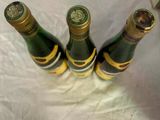 three bottles of beer sitting on top of a white sheet