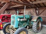 un tracteur qui se trouve dans une grange avec d'autres tracteurs