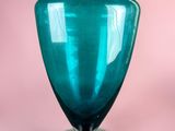 a blue glass vase sitting on top of a metal stand