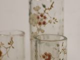 three glass vases with flowers on them sitting on a table