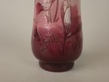 a red vase with a bird on it on a table