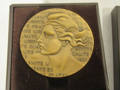 a gold medal with a woman ' s face on it