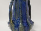 a blue and green vase sitting on a white surface