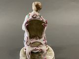 an image of a figurine of a woman sitting on a chair