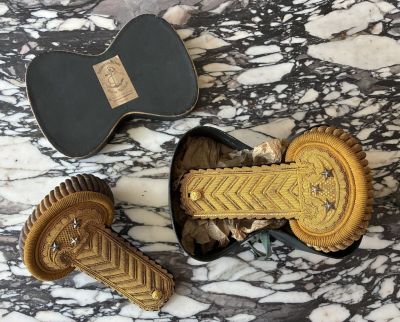 two pieces of gold and black hair clips sitting on top of a marble table