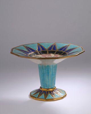 un vase bleu et or posé sur une surface blanche