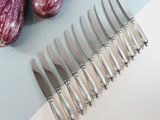 six knives on the table next to some eggplant