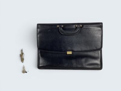 a black leather briefcase with two keys and a keychain on a white surface