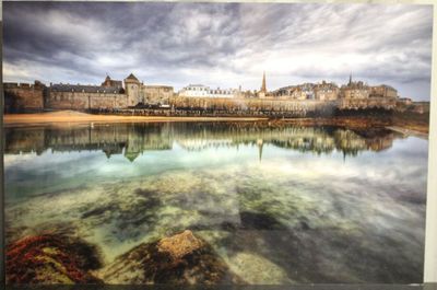 tableau représentant une vue de ville avec un lac au premier plan