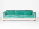 un canapé en velours vert adossé à un mur blanc dans une pièce blanche