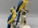 deux figurines représentant des perroquets perchés sur une souche d'arbre