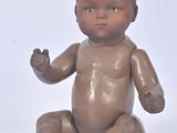 a small baby doll sitting on the floor with its hands in the air
