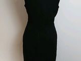 black dress on a mannequin stand against a white wall