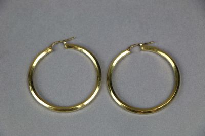 two pairs of gold hoop earrings on a white surface