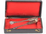 une cuillère ancienne en argent et son repose-cuillère, présentés dans une boîte rouge