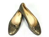 une paire de chaussures pour femme en or, ornées de nœuds, posées sur un fond blanc
