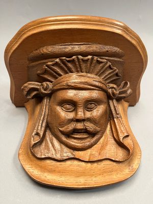 un gros plan sur une plaque en bois sur laquelle est représenté un visage