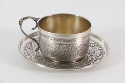 une tasse et une soucoupe anciennes en argent, posées sur une soucoupe, sur un fond blanc
