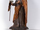 wooden statue of a man holding a flower and a staff