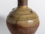 un vase marron posé sur une surface blanche