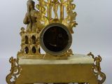 a gold clock sitting on top of a wooden stand