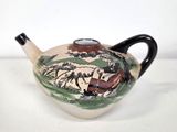 a teapot with a painting on it sitting on a table