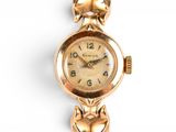 an image of a gold watch with a cat on it ' s face