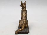 bronze statue of a dog sitting on a rock on a white background