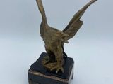 bronze statue of a bird on a black marble base with a white background