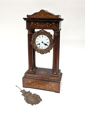 a small clock sitting on top of a table next to a piece of metal