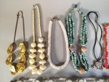 many different necklaces and bracelets displayed on a table