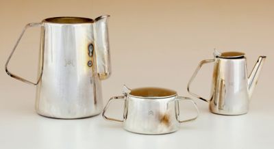 trois pichets en argent et une coupe posés sur une table