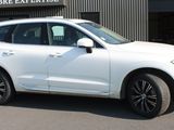 the white volvo suv is parked in front of a building
