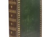 un vieux livre à la couverture verte posé sur une surface blanche