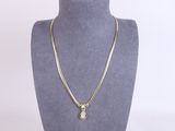 a gold necklace with a diamond pendant on a mannequin