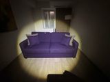 a purple couch sitting in the middle of a dark room