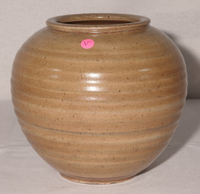 un vase marron sur lequel est collé un autocollant rose