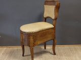 une vieille chaise en bois avec un coussin posé dessus, devant un mur gris