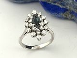 une photo d'une bague sertie d'un diamant et d'un saphir posée sur un rocher